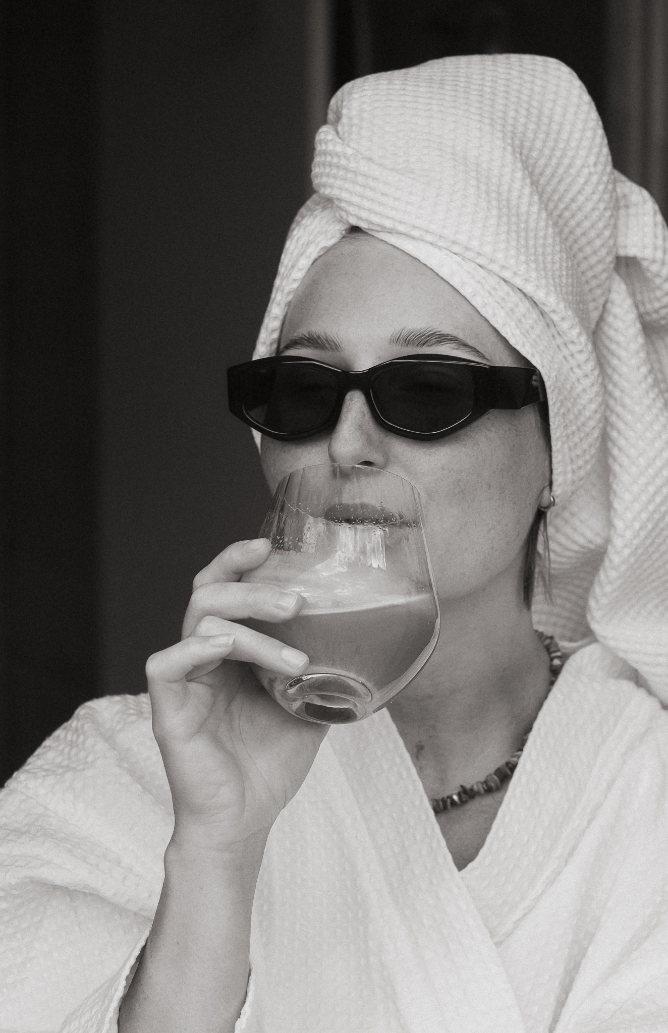 Playful black and white portrait with sunglasses and a drink